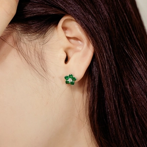 Macro view of a S925 sterling silver plum blossom stud earring with green emerald gemstones