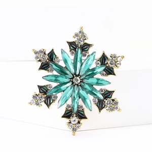 Detailed macro of snowflake brooch with green marquise crystals and black enamel