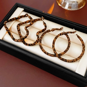 Close-up of leopard print heart and circle hoop earrings in a black jewelry box