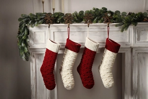 Detail view of four large red and white knitted Christmas stockings with fish scale patterns