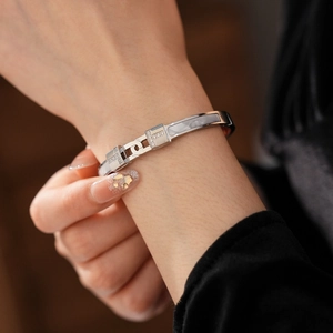 Macro detail of silver T-motif cuff bracelet featuring white mother of pearl and zircons