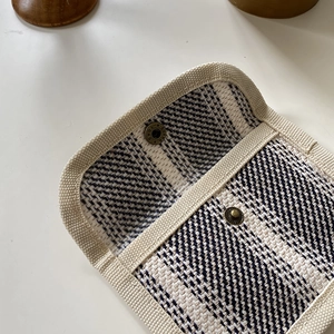 Close-up of black and white tweed card holder with two compartments and bronze button