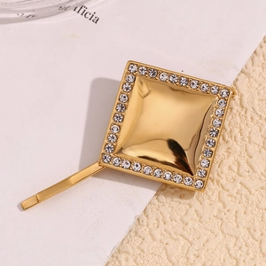Détail macro d'une pince à cheveux carrée dorée avec strass et une finition miroir polie