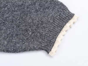 Macro detail of dark grey knit fabric with cream white lace trim and bow accent