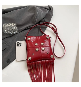 Detail of red rivet crossbody bag with decorative tassels and polished silver studs