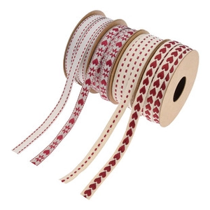 Detail of four rolls of cream ribbons with red heart and star patterns on white background