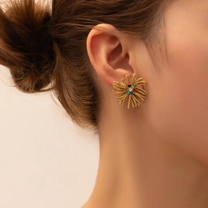 Close-up of vintage golden fan-shaped earrings with colorful zircons on a model's ear