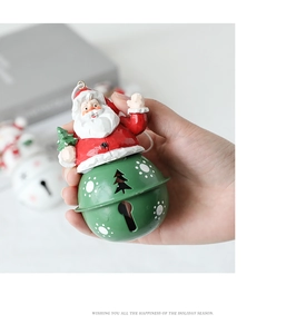 Close-up of Santa Claus resin ornament with a green metal bell and holiday tree