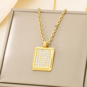 Macro shot of gold square pendant with crystal pavé on champagne textured box