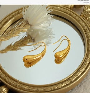 Detail of gold teardrop earrings on vintage mirror with elegant light and shadow