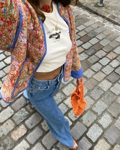 Flat lay of vintage floral stitched jacket with ocean print t-shirt and crochet bag