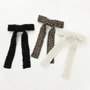 Macro shot of three beaded long ribbon hair bows in black, silver, and pearl white