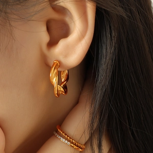 Elegant gold twisted C-shaped hoop earrings with irregular texture worn by a model
