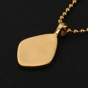 Vue détaillée d'un pendentif trapèze en or brillant et d'une chaîne à billes sur noir