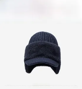 Detailed knit texture of a dark blue winter hat with ear flaps and a small metal logo
