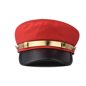 Détail du chapeau en tissu rouge avec bord en cuir noir et bande en métal doré