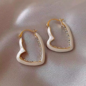 Orecchini a cuore dorati con smalto bianco e zirconi brillanti su seta raffinata
