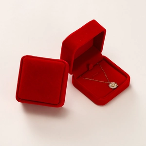 Detail view of red velvet jewelry boxes with a sunburst pendant necklace inside