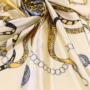 Detailed view of satin scarf featuring gold chains, pearls, and leopard print patterns