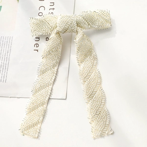 Close-up of handmade cream bow hair clip with silver seed beads in a chevron pattern