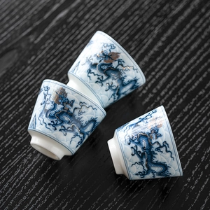 Three elegant blue and white ceramic teacups with golden dragon motifs on a dark wood table