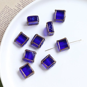 Close-up of royal blue square glass beads with golden edges for jewelry making