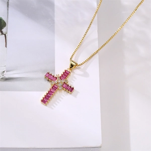 Detailed shot of golden cross necklace with red gemstone and clear crystals on book
