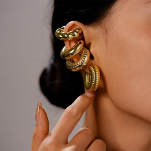 Macro view of gold-colored metal ear cuff set with twisted, smooth, and textured finishes