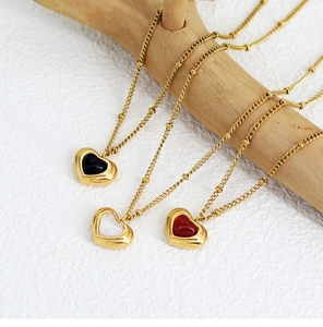 Detailed view of heart pendants in black, white, and red on gold beaded chains