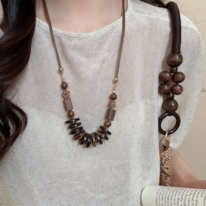 Detail of bohemian necklace with layered wooden beads and floral resin pendants