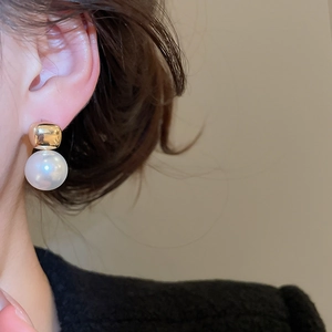 Detail of elegant gold square earring with a white pearl on a model's earlobe