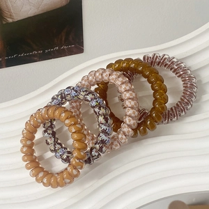 Detail view of 5 colorful spiral hair ties in amber and plaid patterns on display