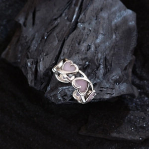 Pink enamel open heart ring in silver finish placed on a black charcoal background