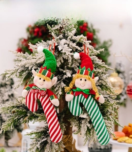 Christmas elf candy cane plush ornaments hanging on a snowy tree with festive decor