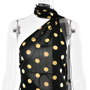 Dettaglio del design allacciato al collo e della fantasia a pois neri e oro sul vestito