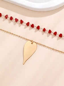 Détail du collier de perles rouges et chaîne dorée avec pendentif en forme de cœur