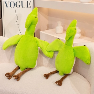 Detail view of two green soft pterodactyl plush toys on a white sofa