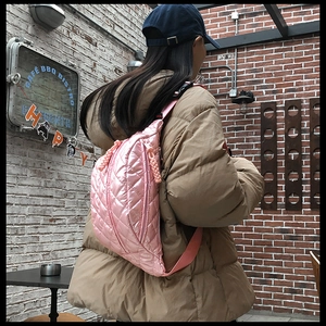 Pink quilted crossbody waist bag shown on a model wearing a khaki winter puffer jacket