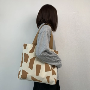 Canvas tote bag with brown geometric patterns and Good Student label on a model
