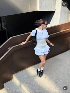 Vue détaillée d'une robe polo blanche à manches courtes avec buste plissé et jupe à volants