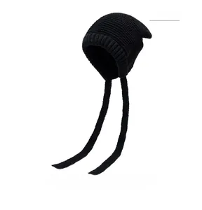 Detailed view of black knitted earflap beanie showing thick yarn texture and ribbed edge