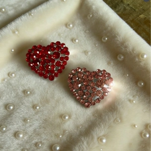 Elegant heart brooch pins with sparkling red and pink crystals on soft white fur