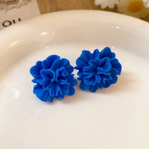 Vue détaillée des boucles d'oreilles fleur en résine bleu vif sur coupelle céramique