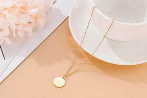 Gros plan d'un pendentif initiale W plaqué or poli sur une fine chaîne sur une tasse