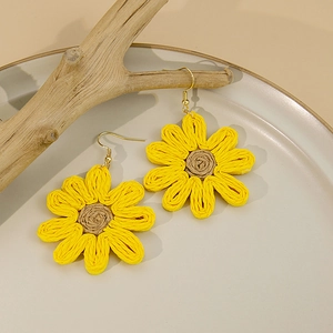 Détail de boucles d'oreilles tournesol tissées main avec des pétales jaunes vifs