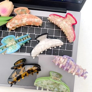 Colorful acetate claw clips in marble and tortoiseshell patterns on a laptop keyboard