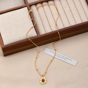 Macro detail of gold tiger eye stone necklace on beige velvet inside a wooden jewelry box