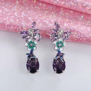 Macro shot of silver floral earrings featuring oval purple amethyst and enamel details