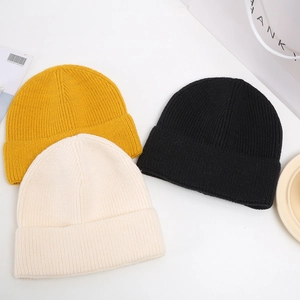 Three knitted beanies in yellow, black and beige colors with a soft ribbed texture