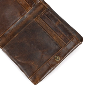 Close-up of vintage dark brown leather wallet showing card slots and bronze metal button